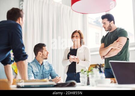 Mature businesswoman with male colleagues discussing project in office Stock Photo