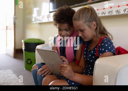 Schoolgirls looking at a tablet computer together in a classroom at elementary school Stock Photo