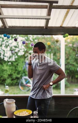 Man using mobile phone while standing in log cabin during party Stock Photo