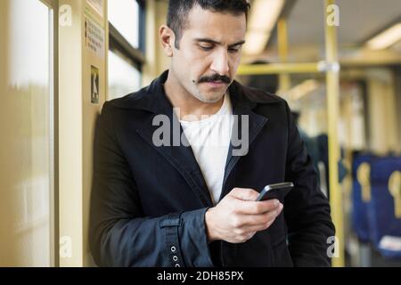 Young man using mobile phone in tram Stock Photo