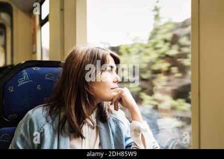 Thoughtful young woman looking through tram window Stock Photo