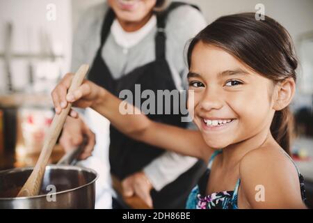 Portrait of happy girl cooking food with grandmother in kitchen Stock Photo