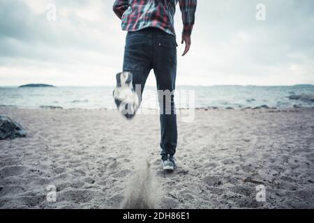 Low section of man running on beach Stock Photo