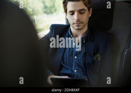 Businessman using digital tablet in train Stock Photo