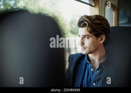 Thoughtful businessman looking through train window Stock Photo