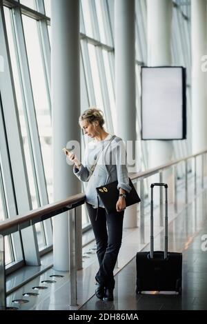 Businesswoman using smart phone at airport Stock Photo