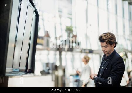 Businessman checking the time by arrival departure board at airport Stock Photo