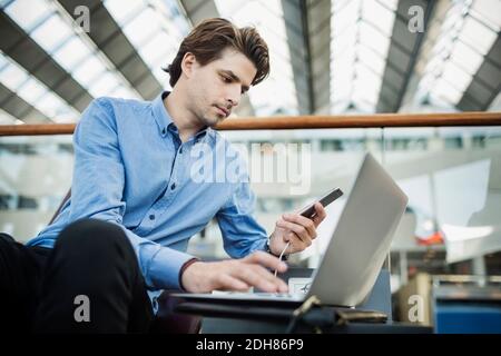 Businessman using laptop and smart phone at airport lobby Stock Photo