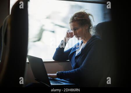 Businesswoman using laptop in train Stock Photo