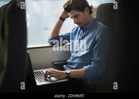 Businessman using laptop while traveling in train Stock Photo