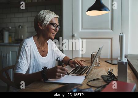Mature female designer working late at home office Stock Photo