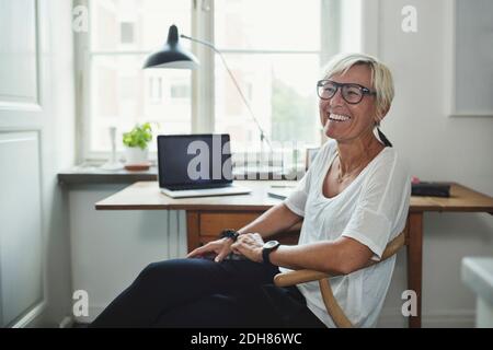 Happy industrial designer looking away while sitting at home office Stock Photo