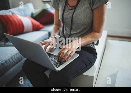 Midsection of industrial designer working on laptop in living room Stock Photo