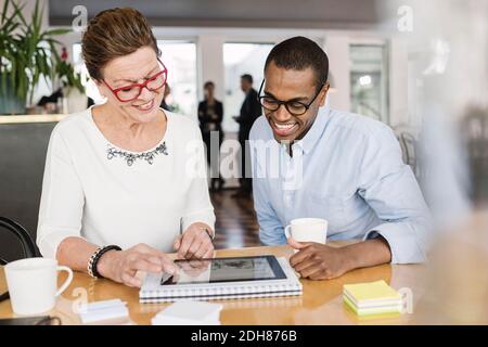 Smiling business people using digital tablet at board room Stock Photo