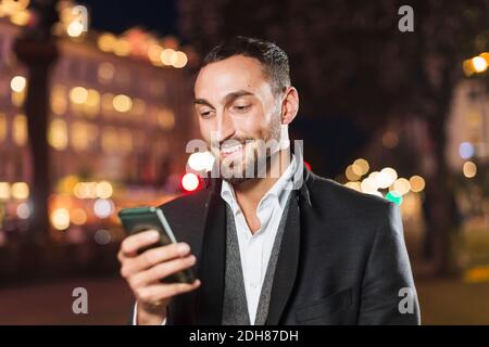 Happy man using smart phone in city at night Stock Photo