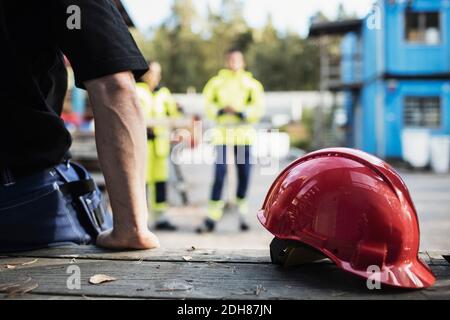 Red hardhat by carpentry teacher leaning on table outdoors Stock Photo