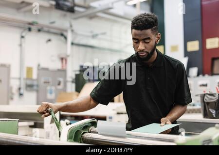 Young male student operating machine in workshop Stock Photo