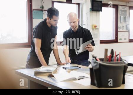 Teacher assisting student on project in training class Stock Photo