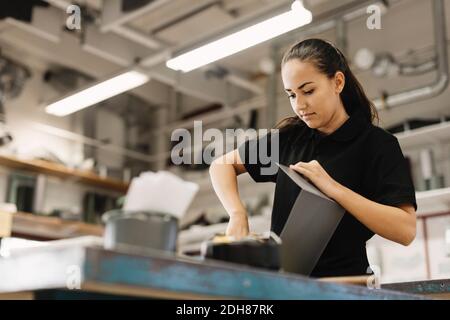 Young woman working on sheet metal at table in workshop Stock Photo
