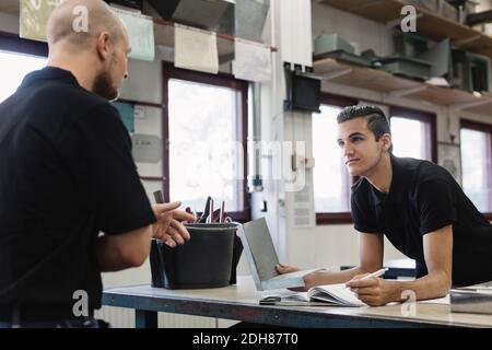 Young male teacher explaining to student in workshop Stock Photo