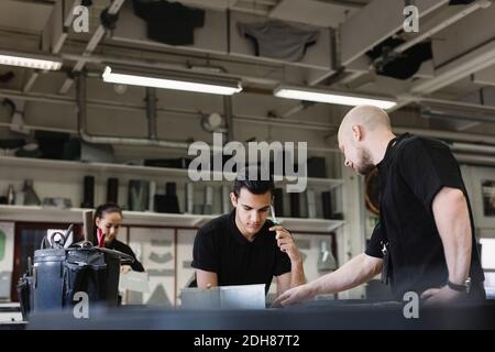 Young male teacher assisting trainee on project in workshop Stock Photo