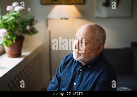 Thoughtful senior man looking away at home Stock Photo