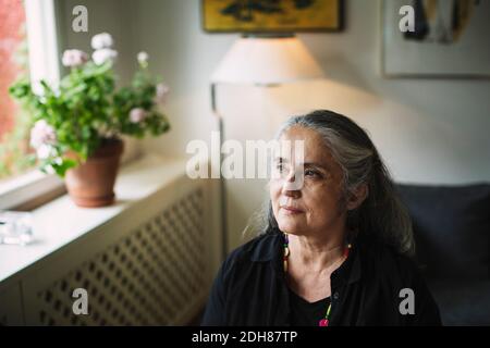 Thoughtful senior woman looking away at home Stock Photo