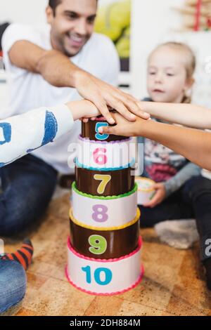 Cropped image of teacher and students piling up hands on number blocks Stock Photo
