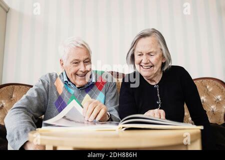 Happy senior couple reading book in living room at nursing home Stock Photo