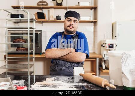 Portrait of young man standing with arms crossed in kitchen Stock Photo