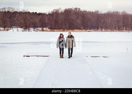 Couple walking on snow covered landscape Stock Photo