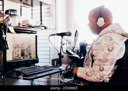 Side view of disabled man wearing headphones while looking at computer Stock Photo