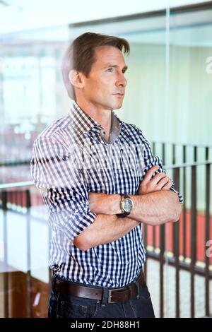 Handsome mature man standing with arms crossed Stock Photo