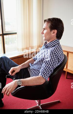 Mature businessman thinking while sitting on chair in office Stock Photo