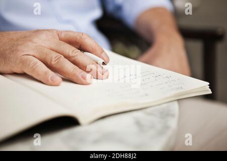 Close up of mature man's hand holding pen with book Stock Photo