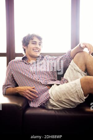 Handsome young man sitting on sofa relaxing Stock Photo