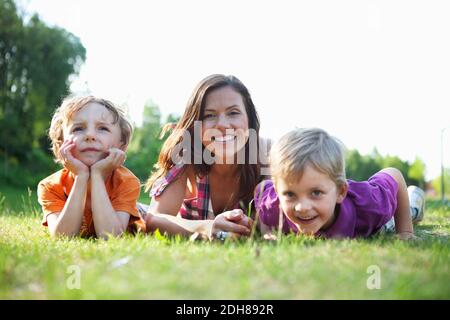 Portrait of a happy mother and children lying on grass Stock Photo