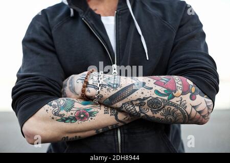 midsection of a tattooed man with arms crossed 2dh8944