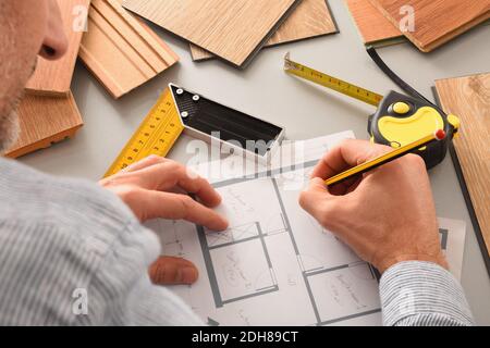 Hands on designer on desk writing on blueprints developing interior project with wood samples and tools. Elevated view. Stock Photo