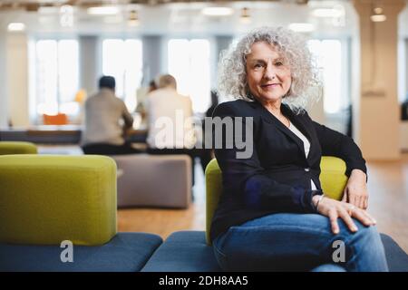 Portrait of senior woman sitting on couch at corridor Stock Photo