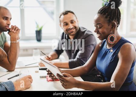 Friends looking at woman using digital tablet in language class Stock Photo