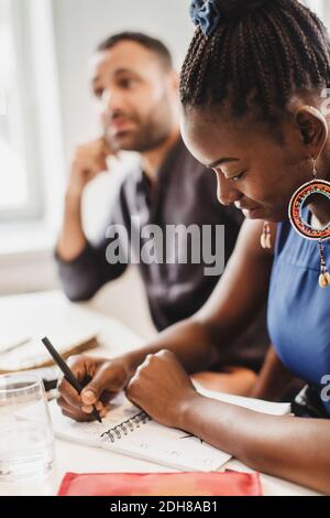 Smiling woman writing in notebook at language class Stock Photo