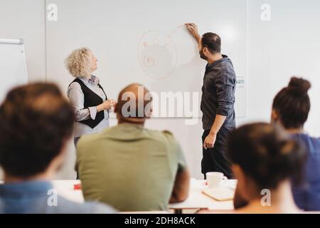 Teacher and students looking at man writing on whiteboard in language class Stock Photo