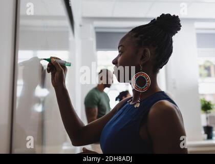 Side view of student writing on whiteboard in language class Stock Photo