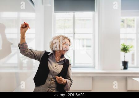 Smiling teacher writing on whiteboard in language class Stock Photo