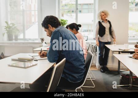 Teacher explaining while students writing in language class Stock Photo