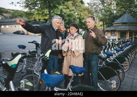 Senior couples using mobile phones at bicycle parking station Stock Photo