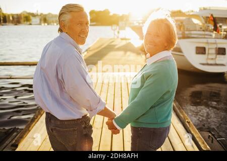 Portrait of happy senior couple holding hands on pier Stock Photo