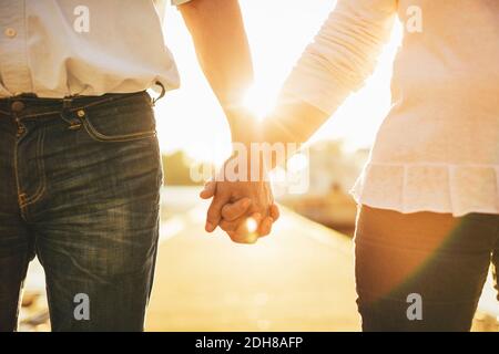 Midsection of loving senior couple holding hands on pier Stock Photo