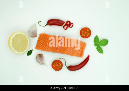 Piece of salmon isolated on white, Garlic, Red chilli pepper lemon, tomato. top  Stock Photo